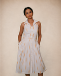 a sleeveless white midi dress with a pointed collar, button front, and a vertical orange ikat pattern,