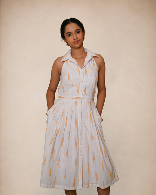 a sleeveless white midi dress with a pointed collar, button front, and a vertical orange ikat pattern,