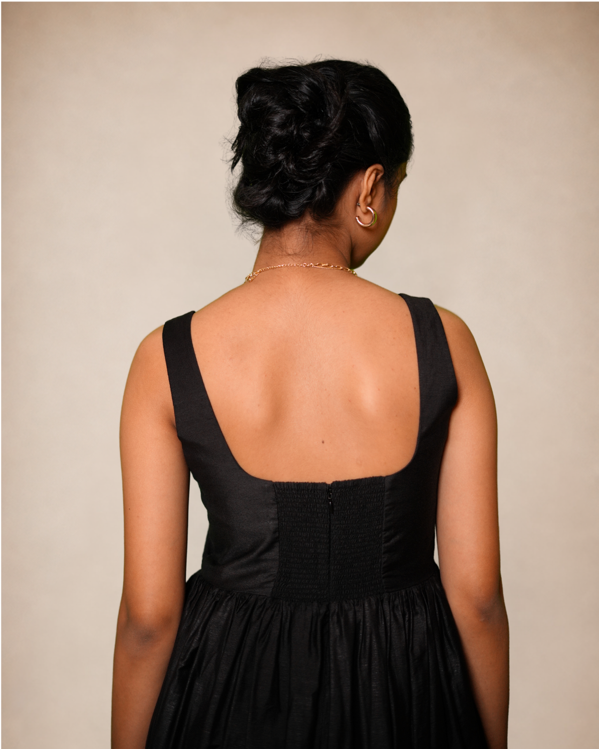 A black sleeveless dress with a structured back and gathered waist