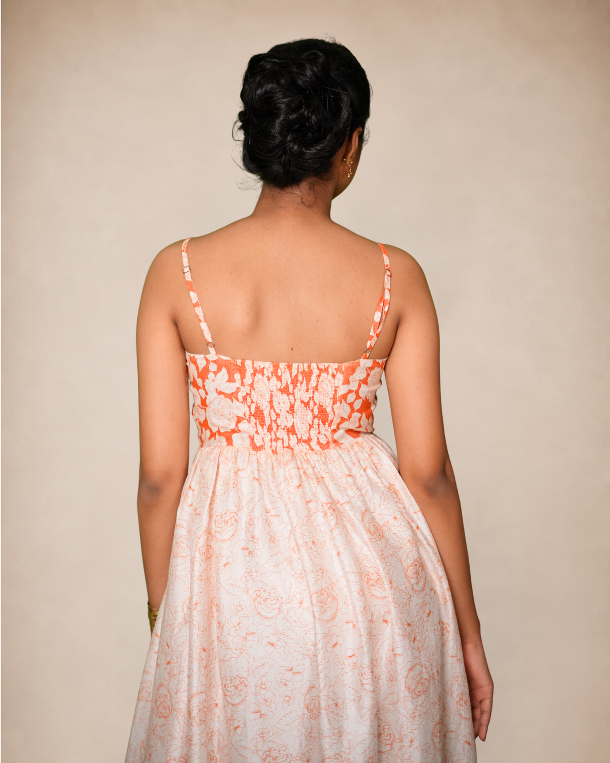 Tantory sleeveless dress with thin straps, a smocked bodice, and a flowing skirt in a white or cream base with an orange abstract floral print