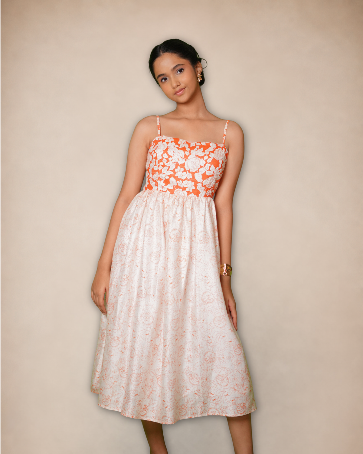 sleeveless midi dress with thin straps, featuring a white and orange floral bodice and a white skirt with a subtle orange pattern